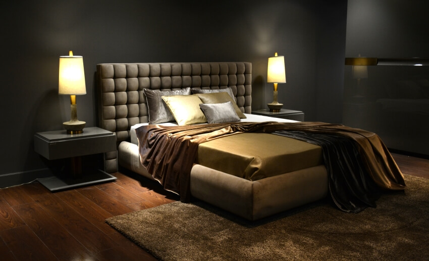 Dark luxurious bedroom with dim romantic lights, carpet, and silk sheets on a large bed