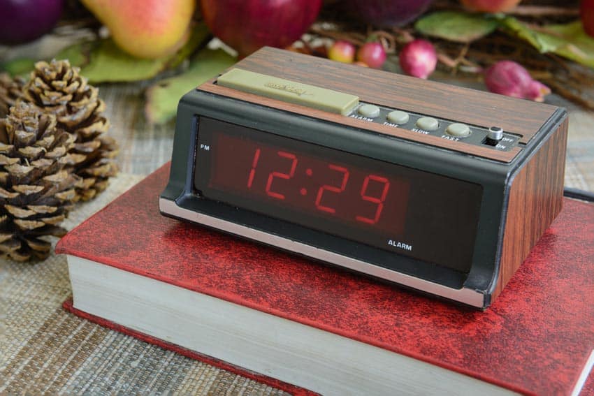 Clock on top of a red book and pine cone