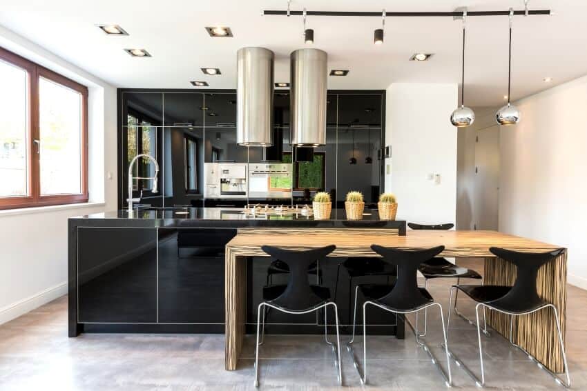 Open kitchen with high gloss black cabinets, track lighting and wood dining table with black chairs