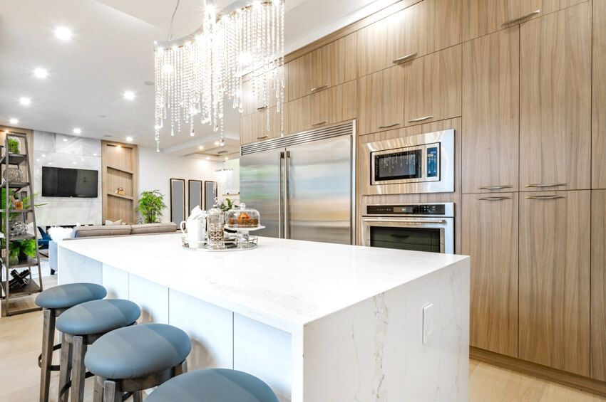 Elegant kitchen with crystal chandelier, waterfall marble, island, and laminate cabinets