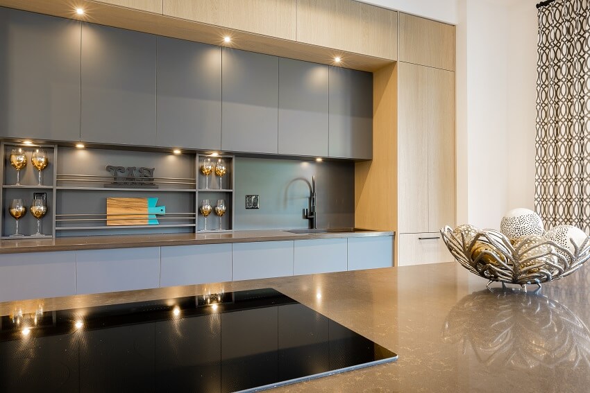 Elegant kitchen with grey backsplash and cabinets, and island with decor and ceramic cooktop