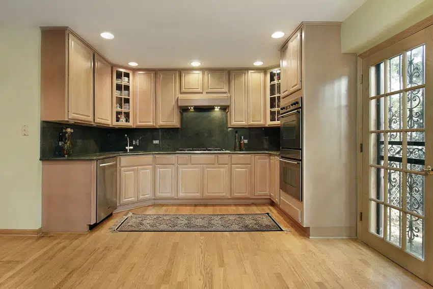 Empty kitchen with pickled oak cabinets, backsplash, countertop, and wood floor