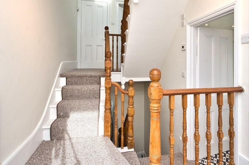 Entrance hallway and stairs with carpet runner and natural wood banister