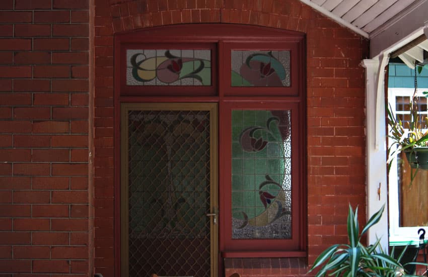 Front door with security screen, and brick wall