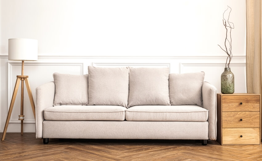 Beige sofa with floor lamp, and table with drawers