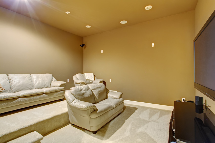 Home theater with beige painted walls, couch, sofa chairs, and ceiling lights