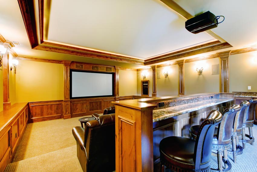 Home theater with painted walls, tray ceiling, bar counter, and chairs