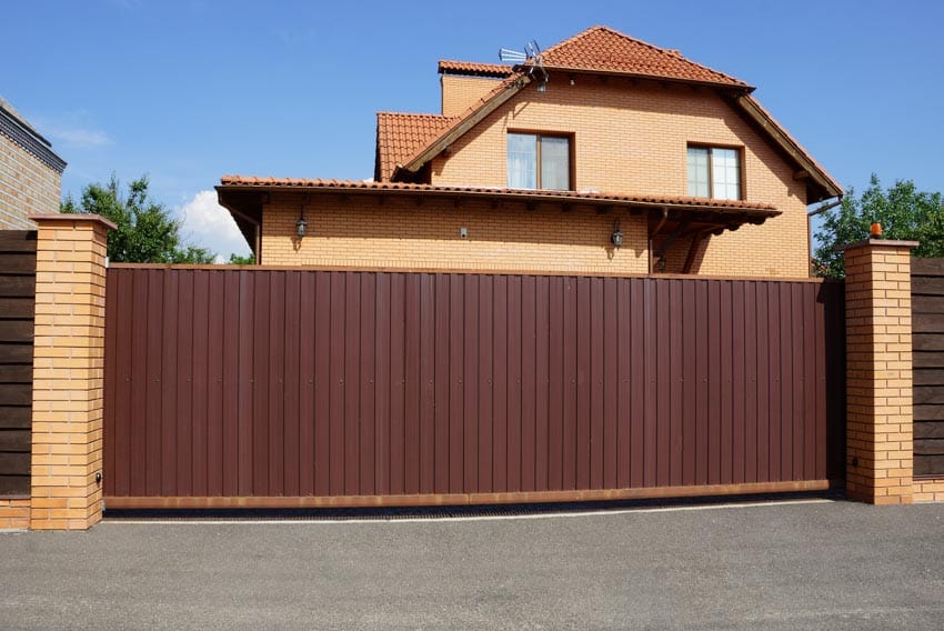 House exterior with brown composite fencing, pitched roof, gate, and windows