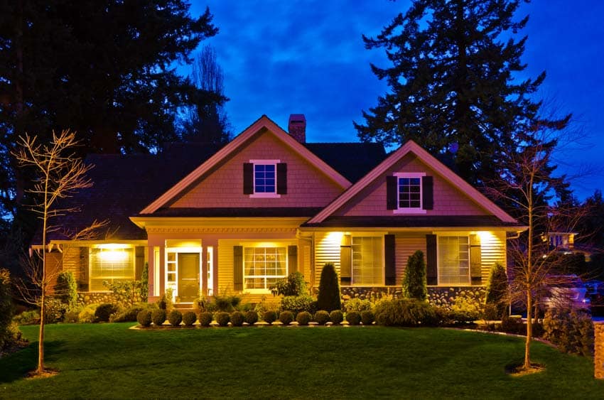 House exterior with color changing landscape lighting, pitched roof, windows, and doors