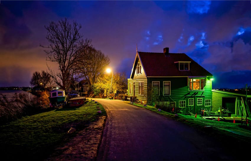 House exterior with color changing landscape lights, pitched roof, and chimney