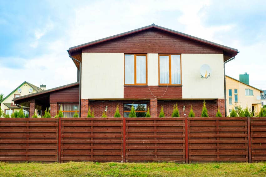 House exterior with mahogany fencing, pitched roof, and windows