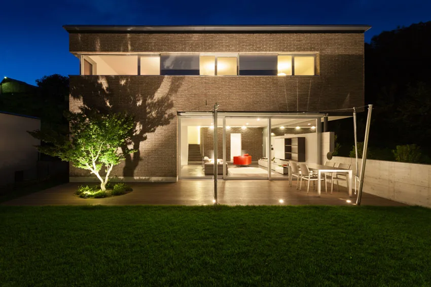 House exterior with deck, glass windows, doors, and landscape lights