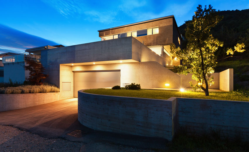 House exterior with driveway, outdoor lighting, and flat roof 