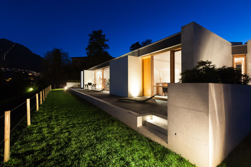 House exterior with front lawn, and outdoor lighting system