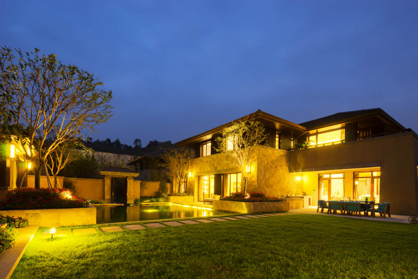 House exterior with landscape lighting, pool, windows, and lawn