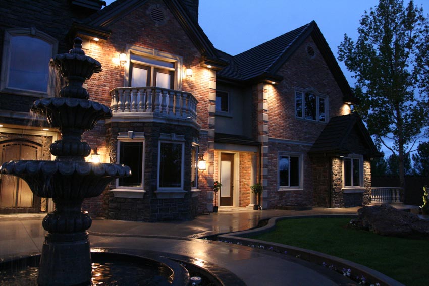House exterior with outdoor lighting, windows, front lawn, and fountain