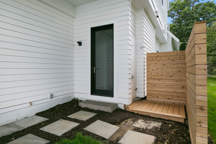 House with white siding, wood shower, and glass door