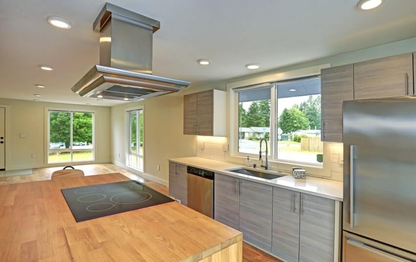 Kitchen boasts kitchen island with a hood, gray shaker cabinets, and quartz and wood countertops