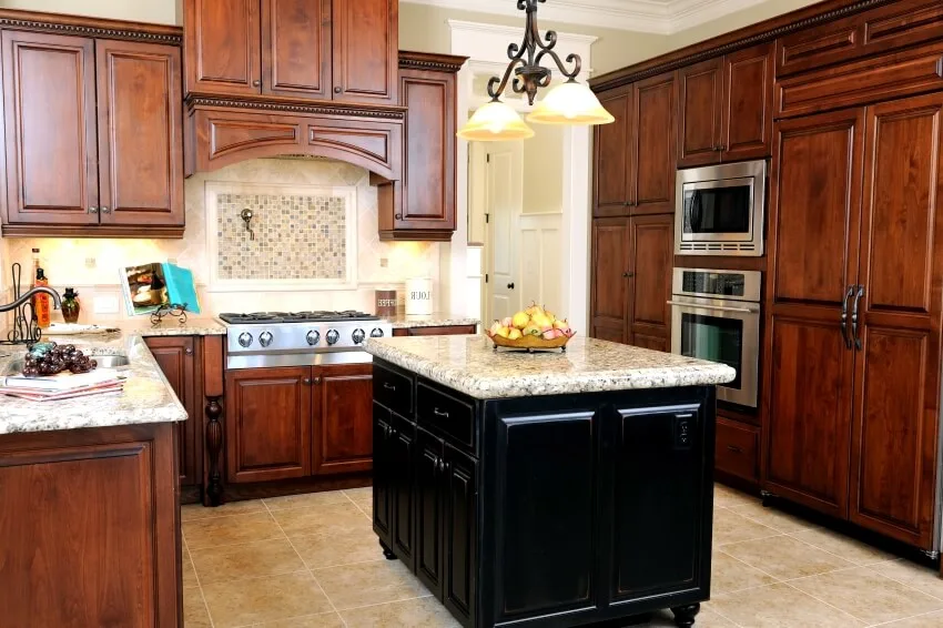 Kitchen interior with tile floor, cherry cabinets, and black island with granite countertop