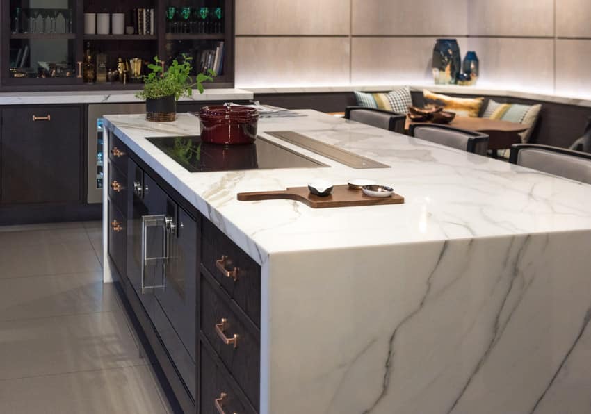 Kitchen waterfall island with stove, countertop, drawers, and oven