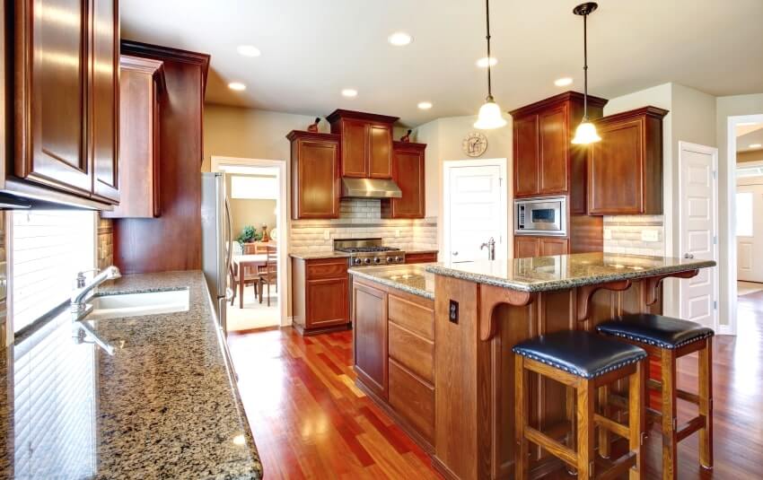 Kitchen room with oak cabinets, granite countertops, island with bar counter and barstools