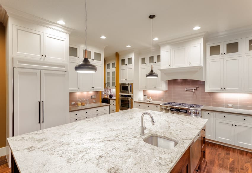 Kitchen with center island, countertop, pendant lights, wood flooring, backsplash, and cabinet lighting