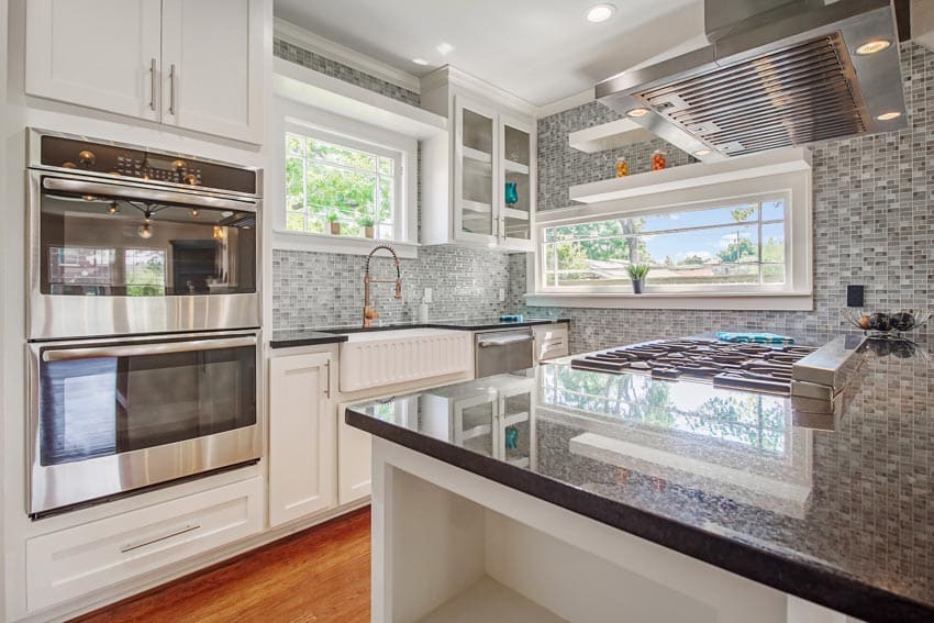 Kitchen with center island with black granite, and mosaic tile walls