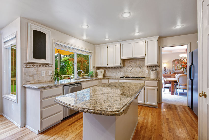 Kitchen with rounded countertop island, white cabinets, and ceiling lights