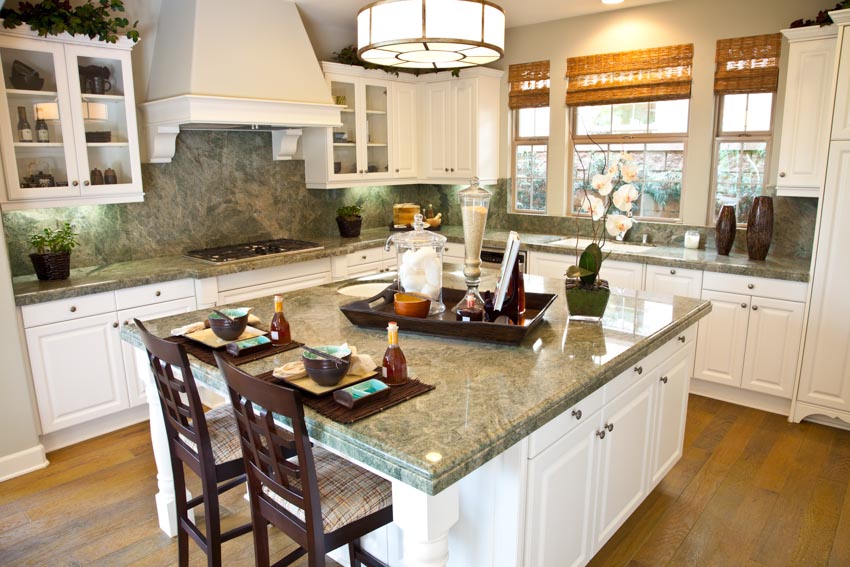 Kitchen with center island, granite backsplash, white cabinets, window, and wood floor