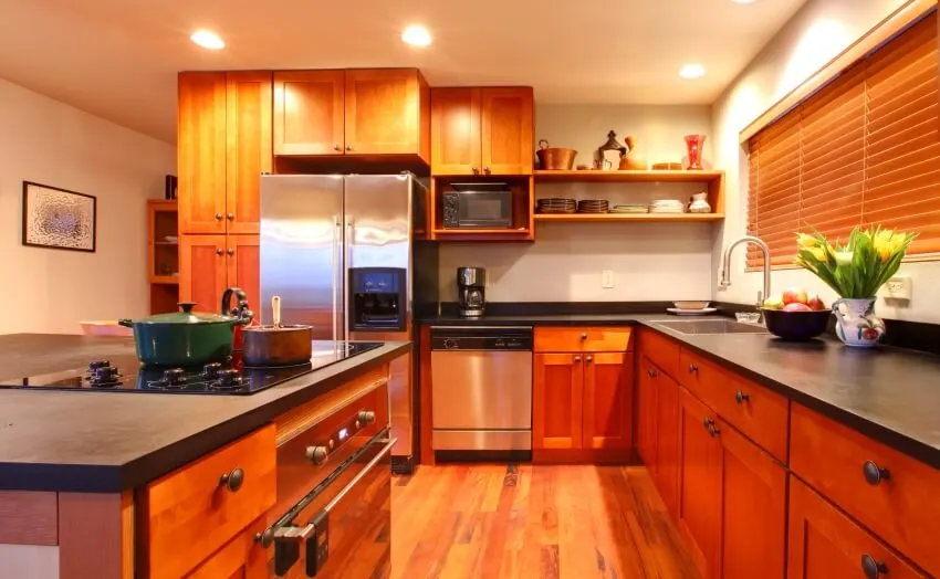 Kitchen with cherry wood cabinets, hardwood floor, black countertop, shelves, and recessed lighting