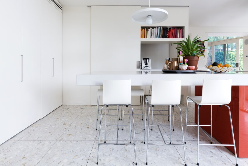 Kitchen with clean crisp white modern island with high chairs, and terrazzo floor