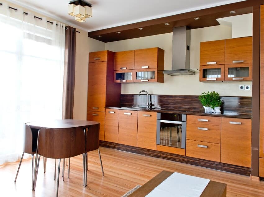 Kitchen with dark brown countertop, light brown cabinets, and small table with chairs