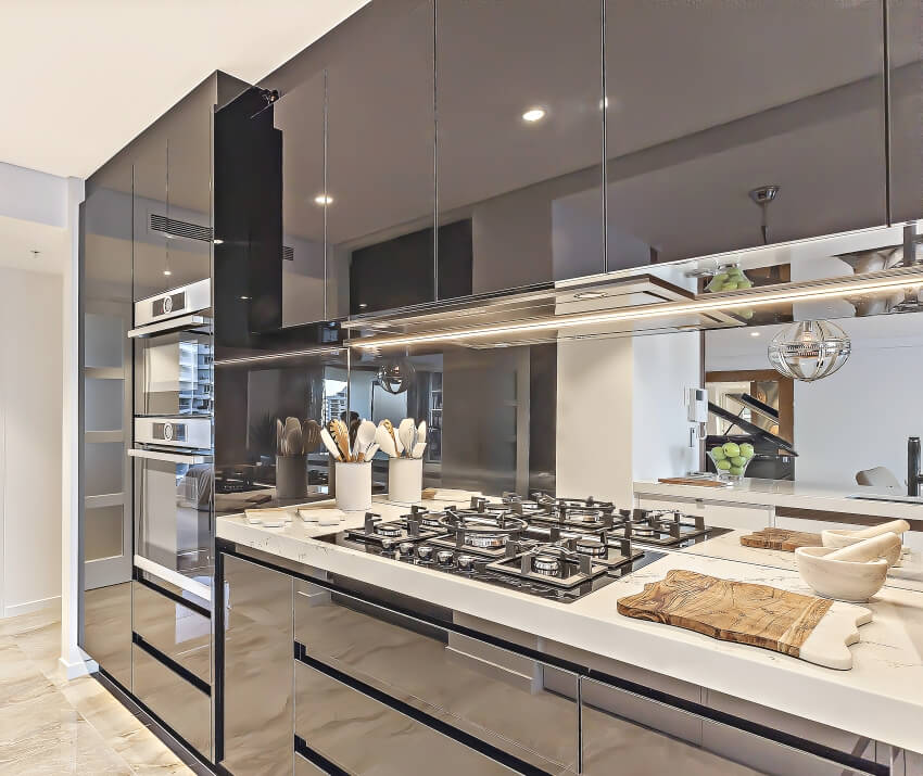 Kitchen with glossy laminate cabinets, marble floor, and mirror backsplash