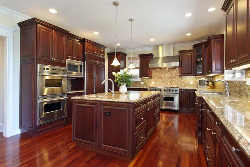 Kitchen with granite backsplash, center island, countertop, wood flooring, cabinets, and pendant lights