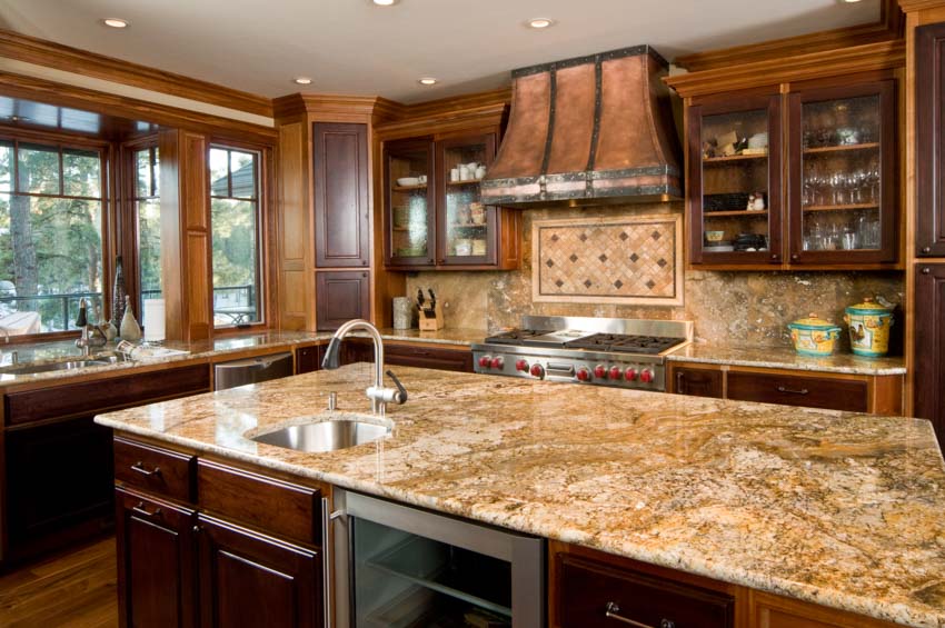 Kitchen with granite backsplash, countertop, center island, wood cabinets, range hood, and windows