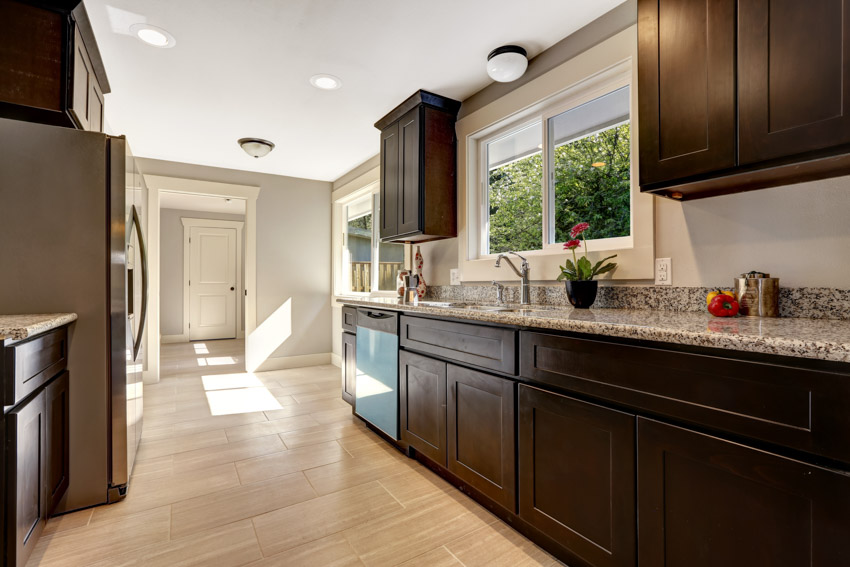 Kitchen with dark wooden cabinetry, granite surface counter, and 4 inch wall splash