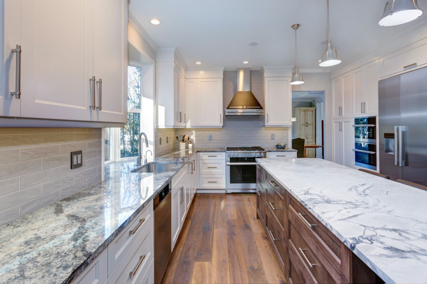 Kitchen with granite countertops, white cabinets, pendant lights, and dark wood floors