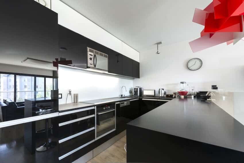 Kitchen with high gloss black cabinets, red ceiling lamp, and under cabinet lighting