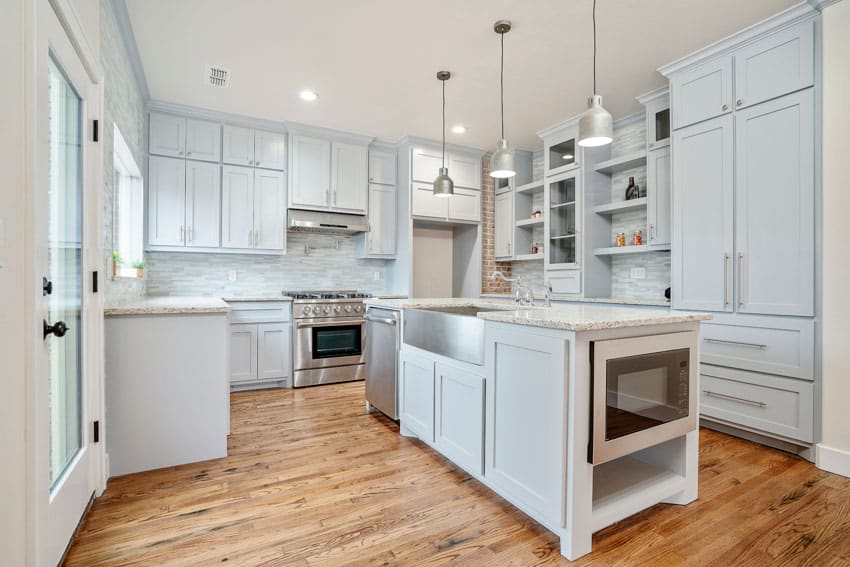 Kitchen with countertop made of quartzite, hanging lights, and white recessed cabinets