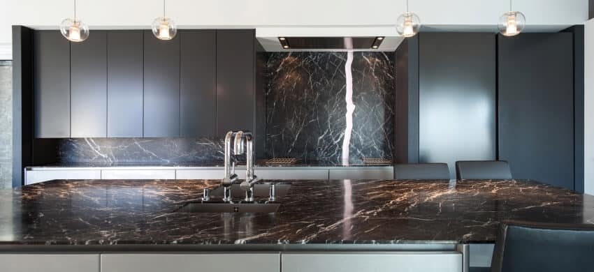 Kitchen with marble countertop and backsplash, pendant lights, and black gloss cabinets