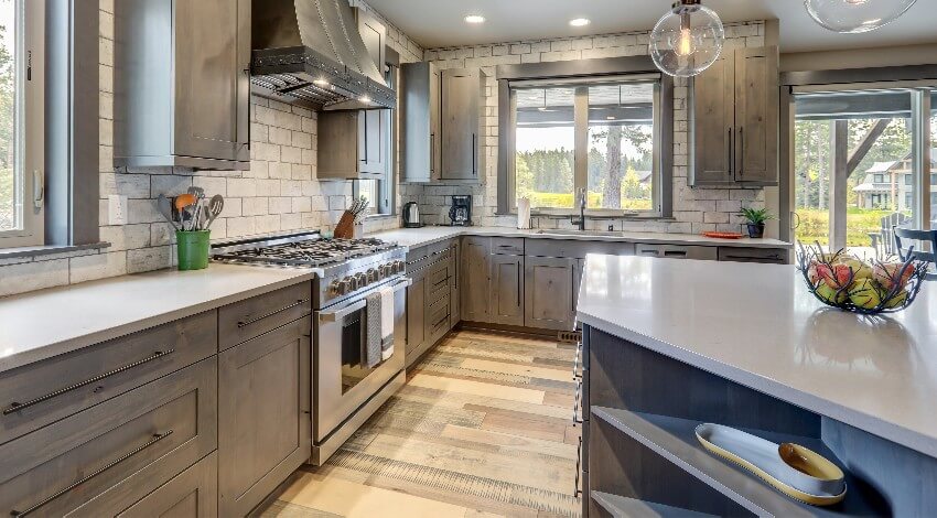 Kitchen with natural tones with rustic modern island, brick backsplash, and laminate cabinets