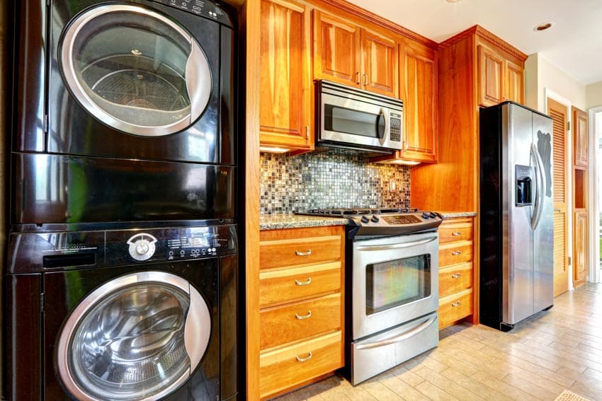Kitchen with stackable washer dryer, wood cabinets, oven, and backsplash