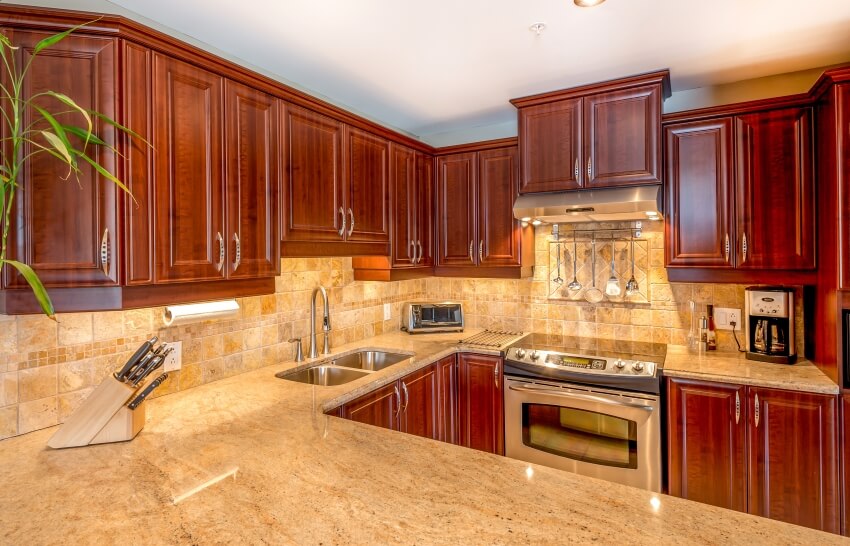Kitchen with stone tile backsplash, granite countertops, and under-cabinet lighting