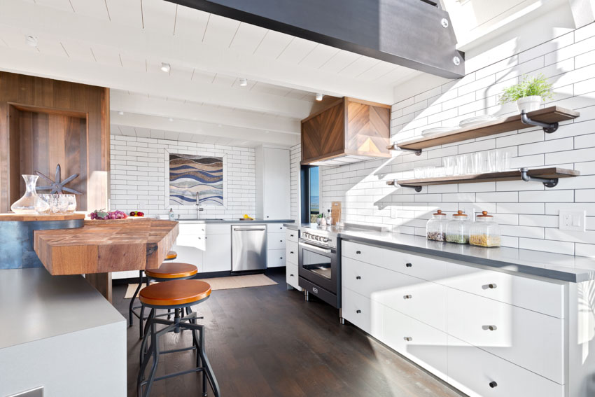 Kitchen with tile backsplash, white cabinets, wood floor, and floating shelves