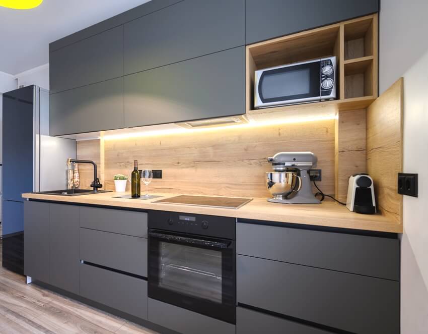 Kitchen with under cabinet lighting, wood countertop and backsplash, and gray laminate cabinets