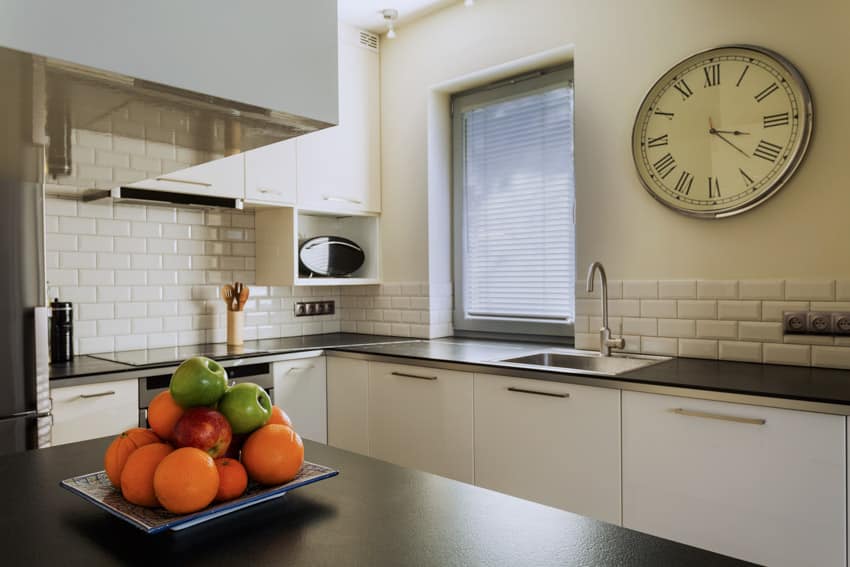 Round clock on wall with subway tiles and chrome sink