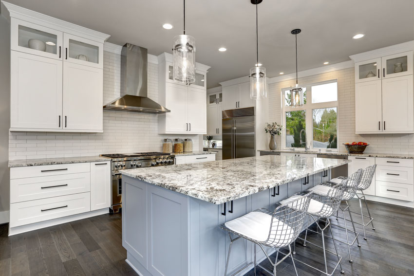 Kitchen with pastel blue island, white tile and cabinets and wood grain floors