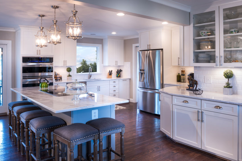 Kitchen with white cabinets, center island, stools, wood flooring, and pendant lights