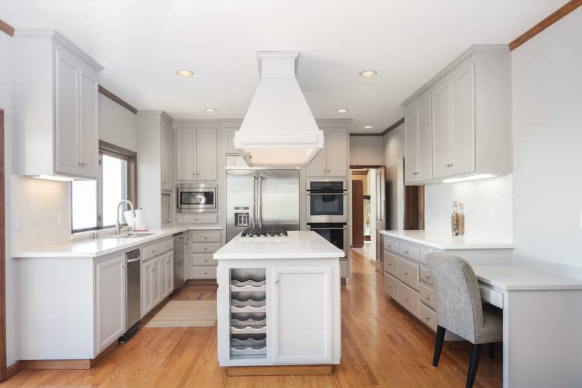 Kitchen with white cabinets, center island, stove, range hood, and wooden floors