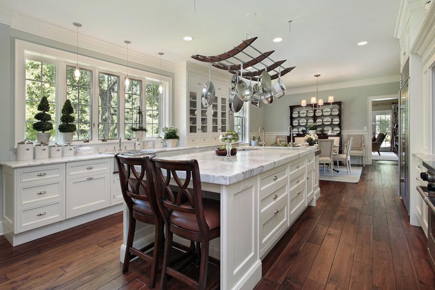 Kitchen with white cabinets, dark wood floors, center island, windows, and pendant lights